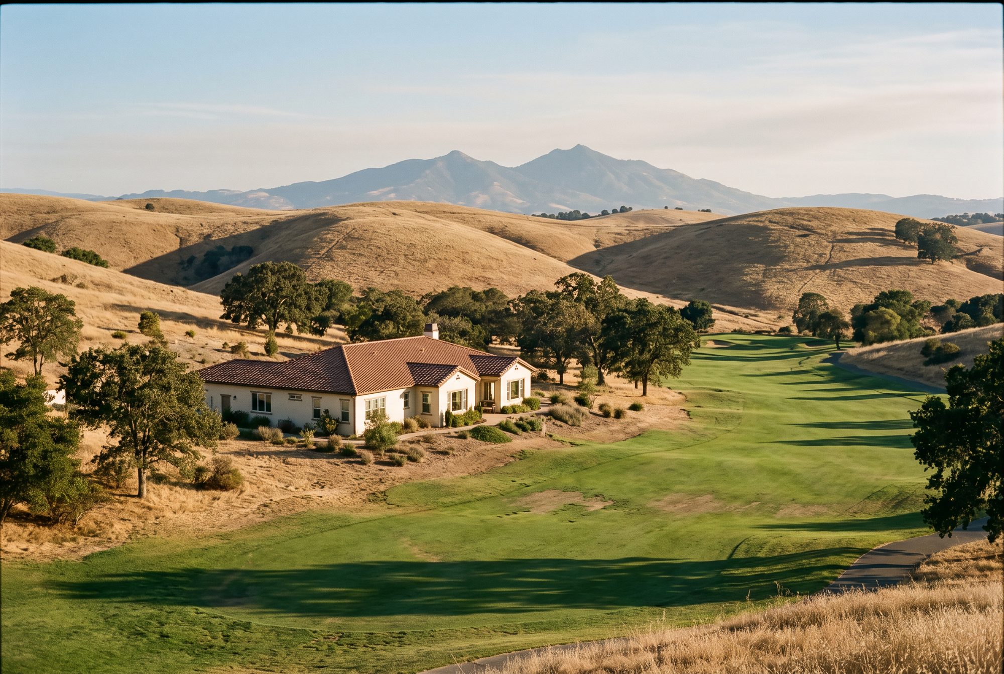 A single-level home with a terracotta tile roof beside a golf fairway in the golden East Bay hills, Mount Diablo on the horizon